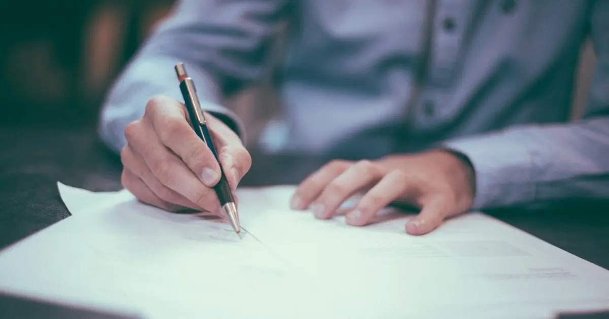 Business owner signing a payment authorization form at a desk, illustrating ACH authorization requirements