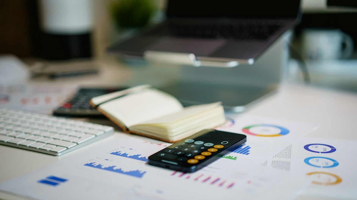 Calculator resting on printed charts beside a keyboard, used to work out an effective card processing rate