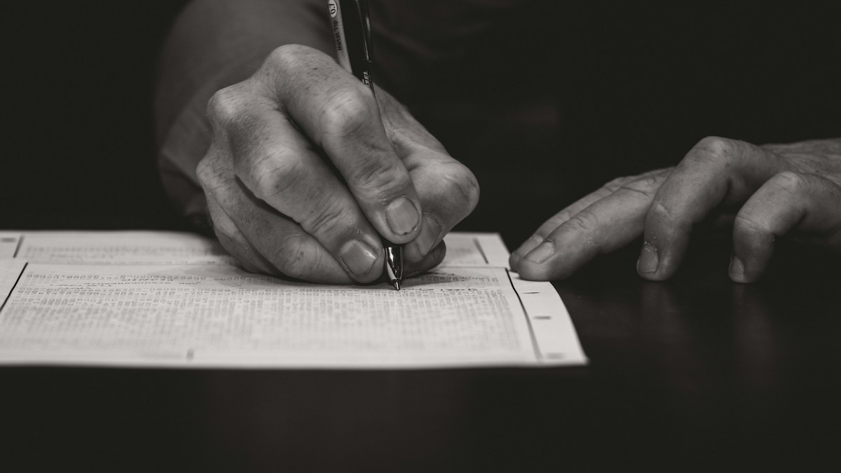 Client signing a travel agent credit card authorization form with a pen to approve trip charges and cancellation terms