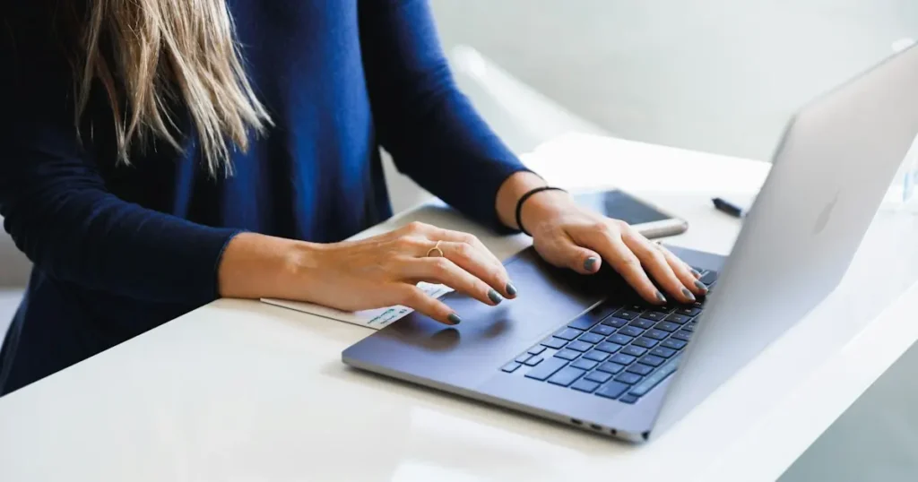 Business owner typing on a laptop at a white desk to pay online, illustrating e-check vs ACH bank payments