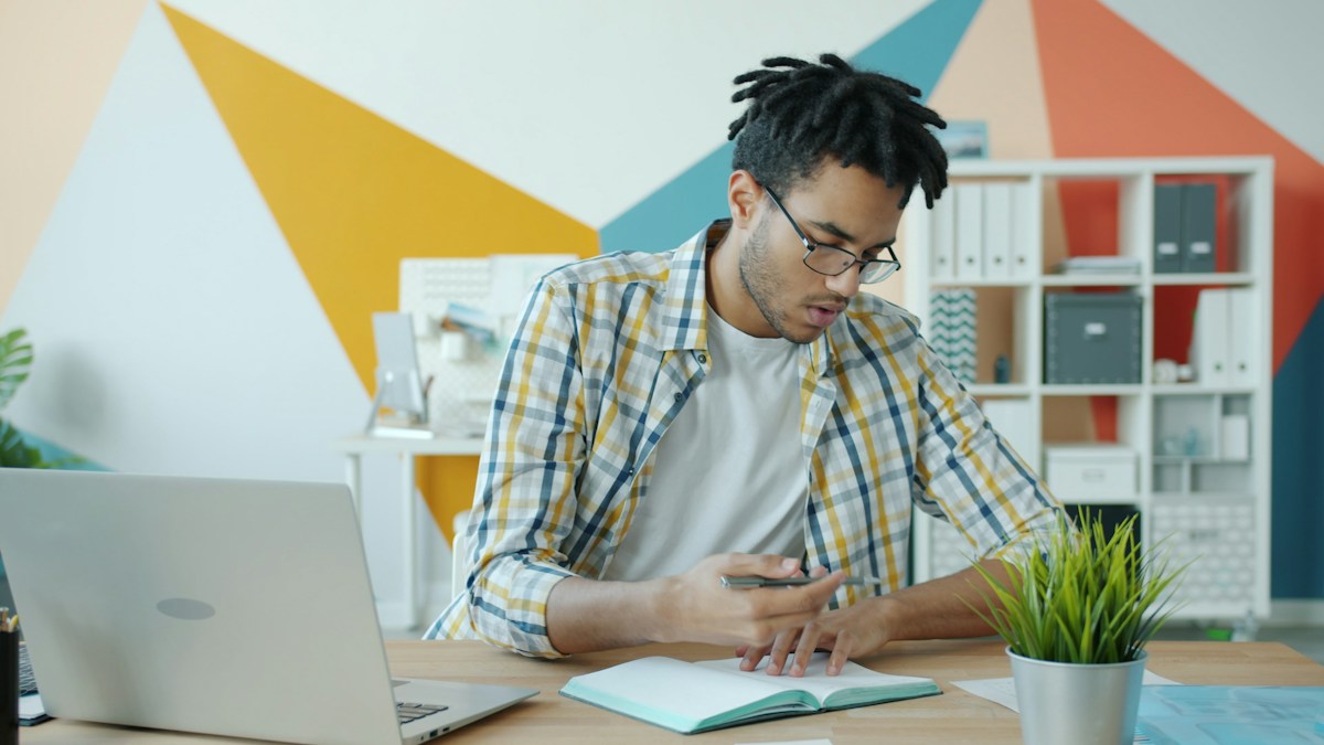 Founder taking notes at a desk with a laptop while planning the business setup for a new supplement brand