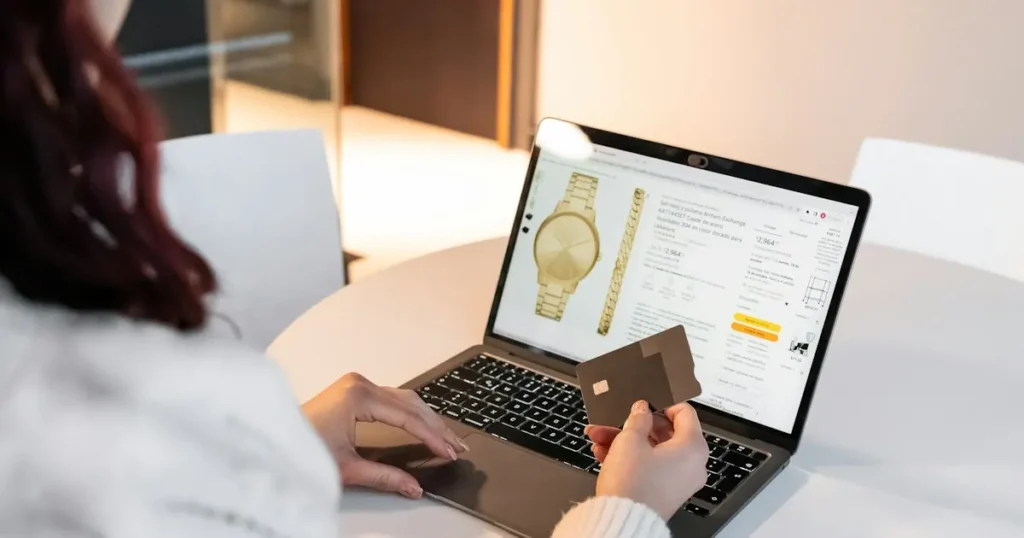 Customer holding a card while shopping online on a laptop, the kind of purchase that can later become a friendly fraud chargeback