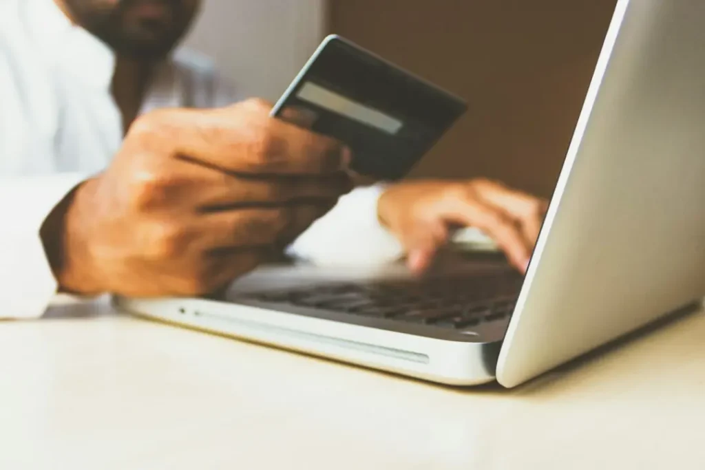 Business owner holding a credit card at a laptop during an online payment