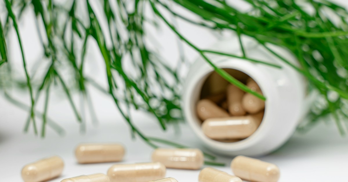 Supplement capsules spilling from a white bottle, illustrating how to start a supplement business