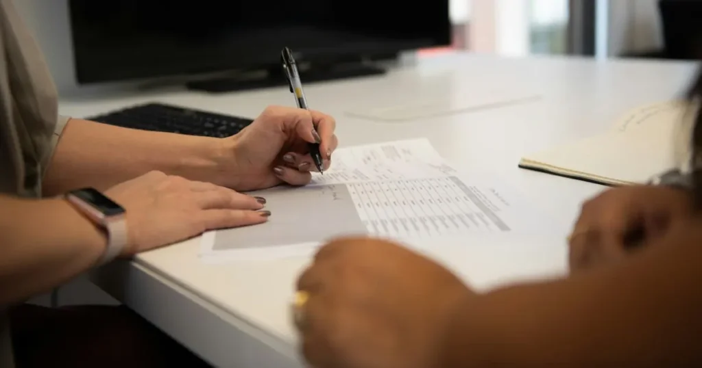Business owner reviewing and signing a printed application at a desk during merchant account underwriting