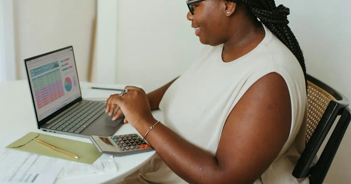 Business owner reviewing a sales report on a laptop with a calculator, checking the merchant category code on her merchant statement
