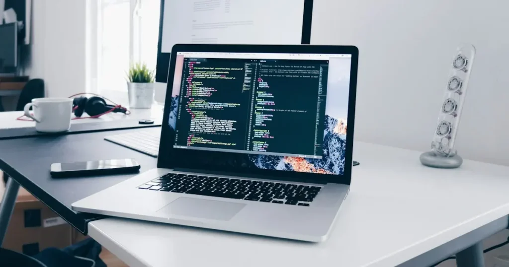 Laptop showing code on a developer's desk while comparing NMI vs Authorize.net payment gateway integrations
