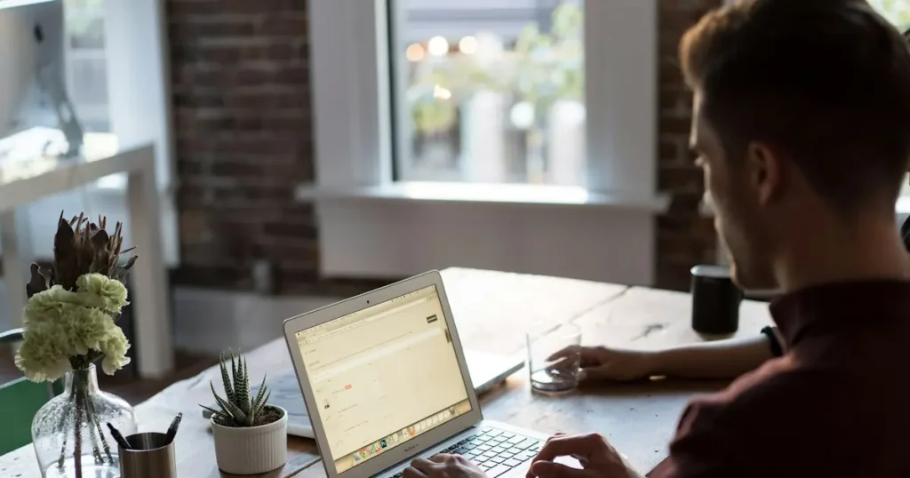 Business owner reviewing ACH payment activity on a laptop at a wooden desk to prepare for the Nacha rule changes 2026