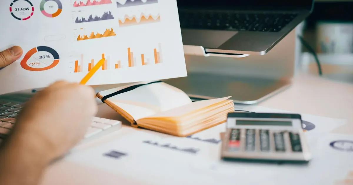 Business owner reviewing cash flow charts next to a calculator and laptop to plan for a rolling reserve on card sales