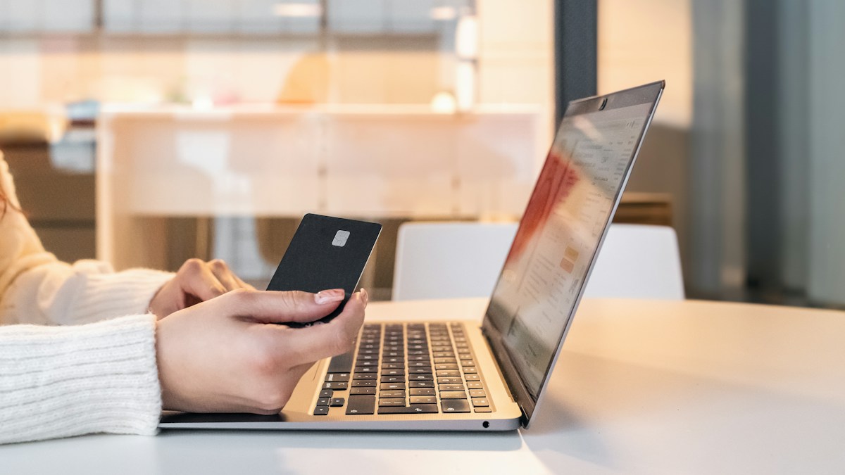 Customer holding a card at a laptop to pay at an online supplement store checkout