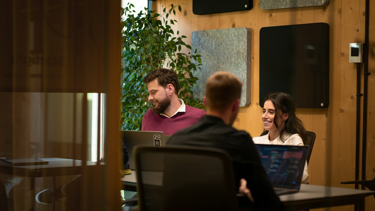 Software agency team talking through a client project around laptops in a meeting room, weighing which payment gateway suits their setup