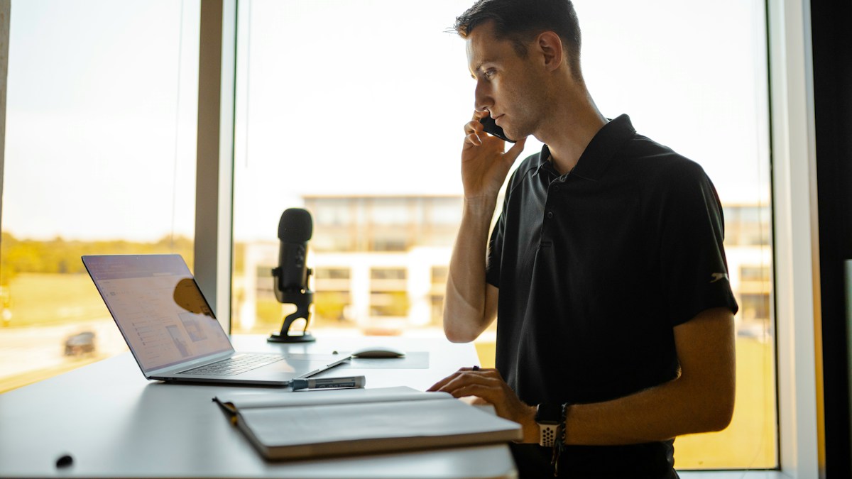 Travel agent on a phone call with a client while entering a card payment on a laptop through a virtual terminal and payment gateway