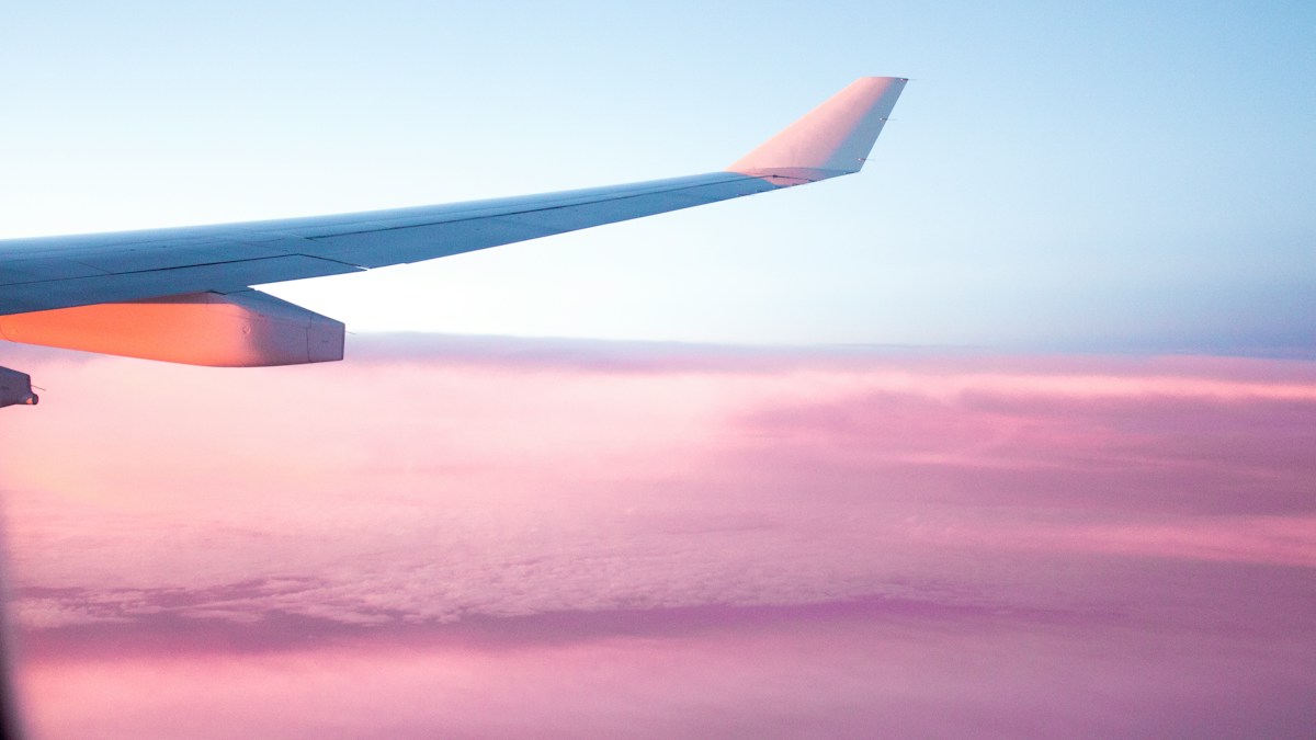 Airplane wing above the clouds, representing trips paid for months before travel and the chargeback risk in travel agency credit card processing