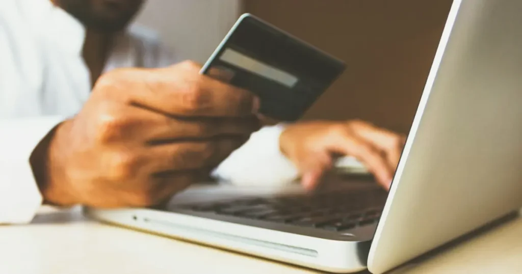 Hands holding a credit card over a laptop during an online checkout, illustrating what makes a business high-risk for card processing
