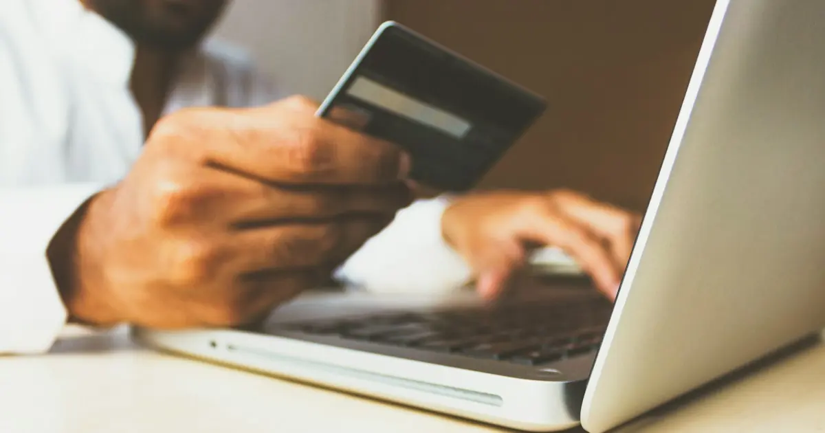 Hands holding a credit card over a laptop during an online checkout, illustrating what makes a business high-risk for card processing