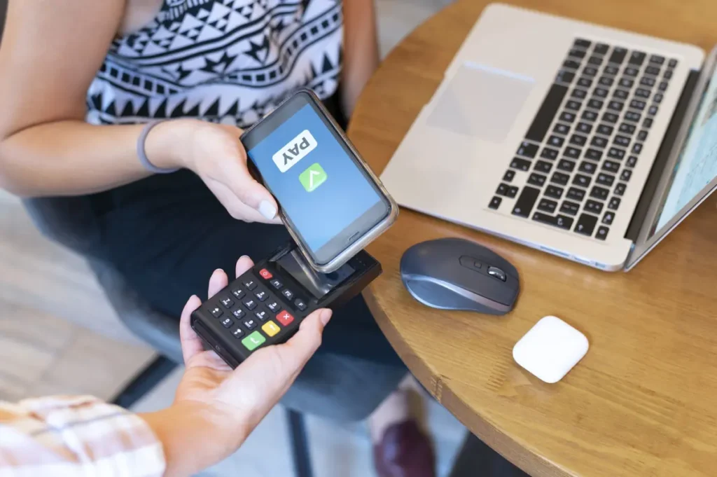 girl paying with mobile phone in a retail shop having merchant account after shopping